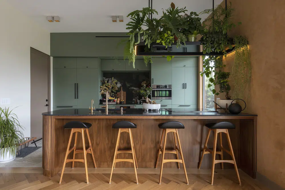 Modern kitchen with mint green cabinets, wooden island and hanging plants